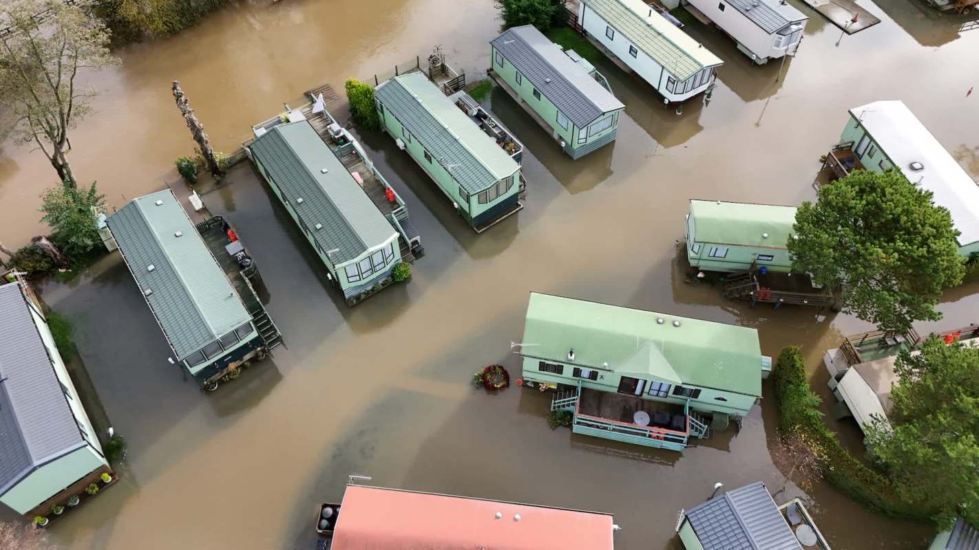 Aerial view of mobile homes partially submerged in floodwater.