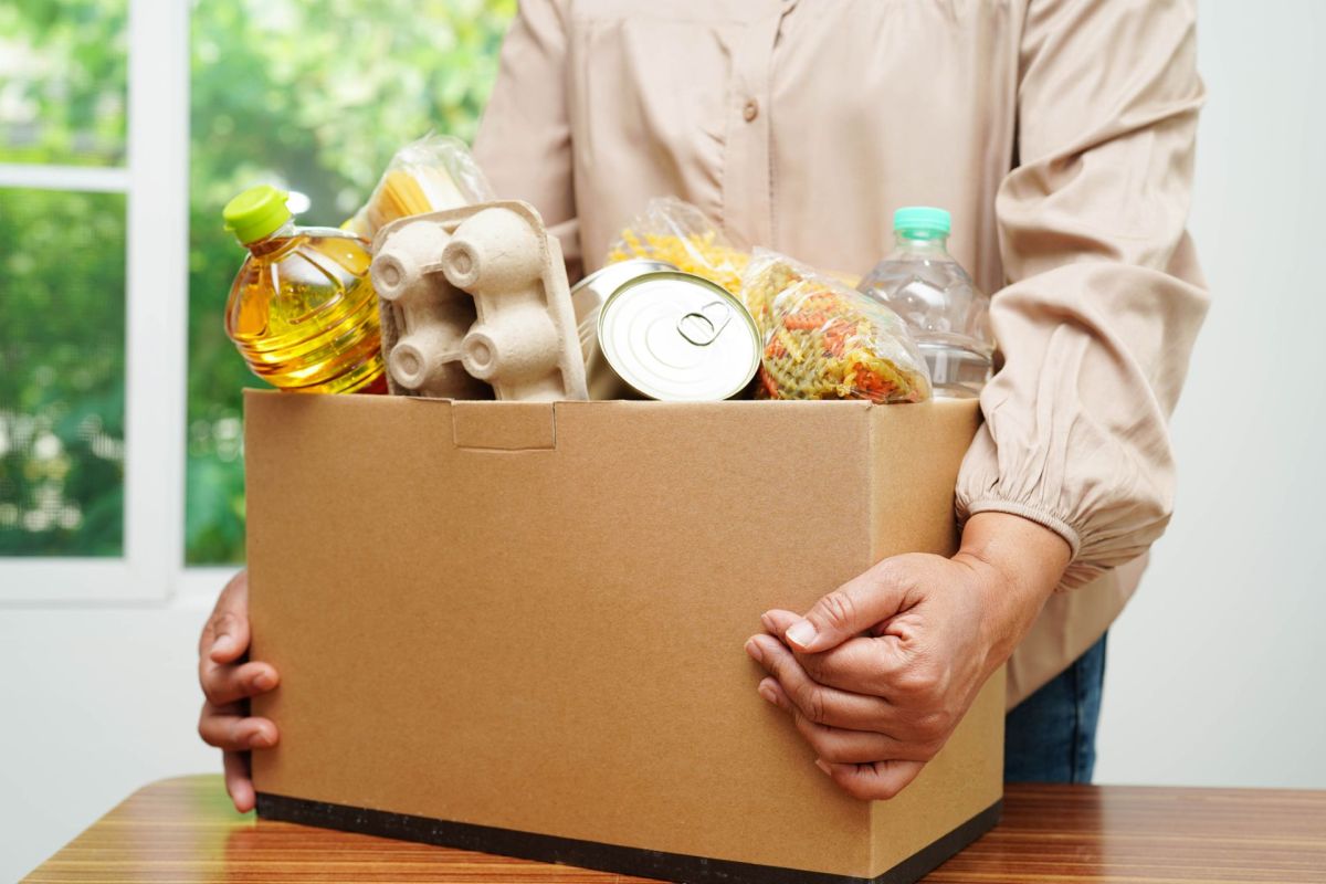 A woman carrying a box of food donations.