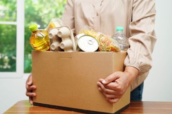 A woman carrying a box of food donations.