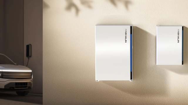 A white charging station and FranklinWH battery mounted on a textured wall beside an electric vehicle.