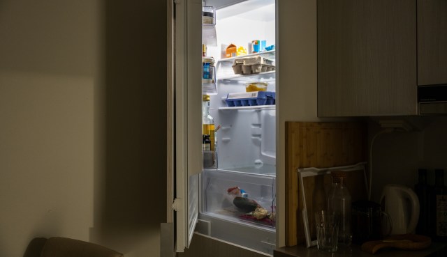 A refrigerator with various food items, including containers, bottles, and vegetables, partially visible inside.