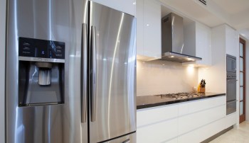 A modern kitchen featuring a stainless steel refrigerator and a gas cooktop with a hood.