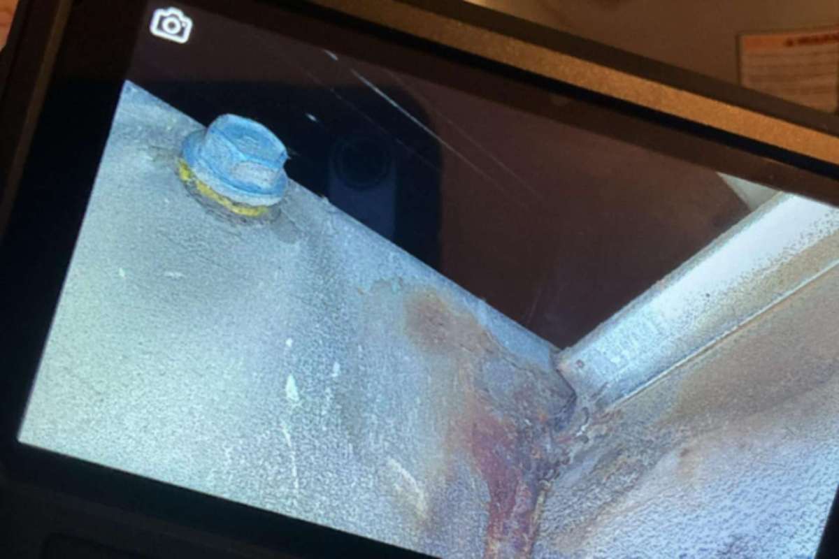 An inspection camera showing a metal surface with a bolt and signs of corrosion.
