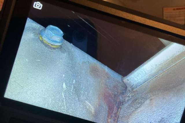 An inspection camera showing a metal surface with a bolt and signs of corrosion.