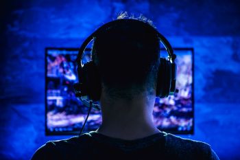 A gamer sitting at a computer with headphones on.