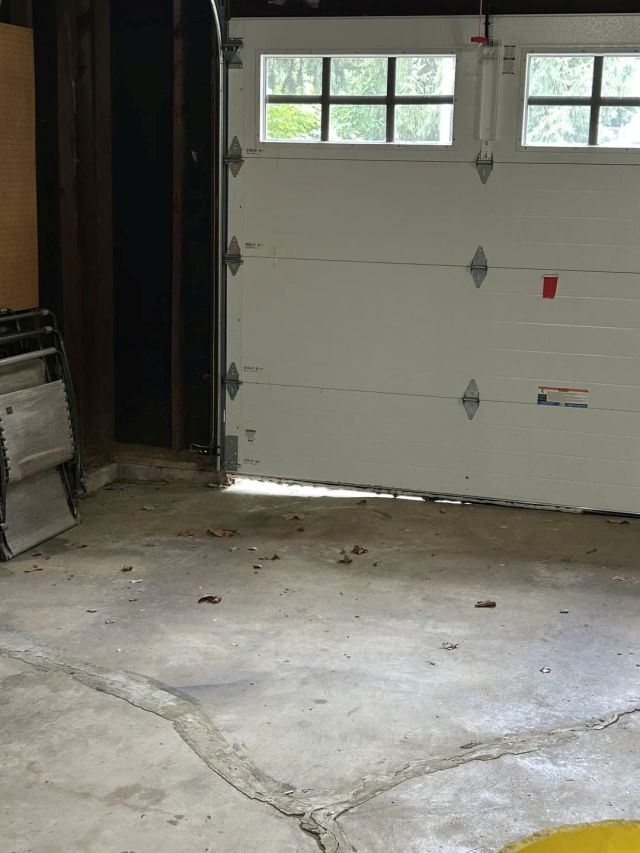 A garage door with a gap at the bottom.