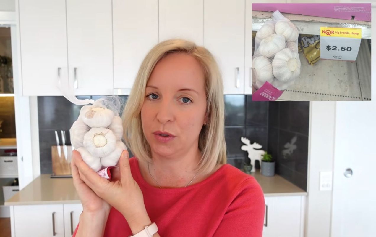 A woman holding a bag of garlic bulbs.