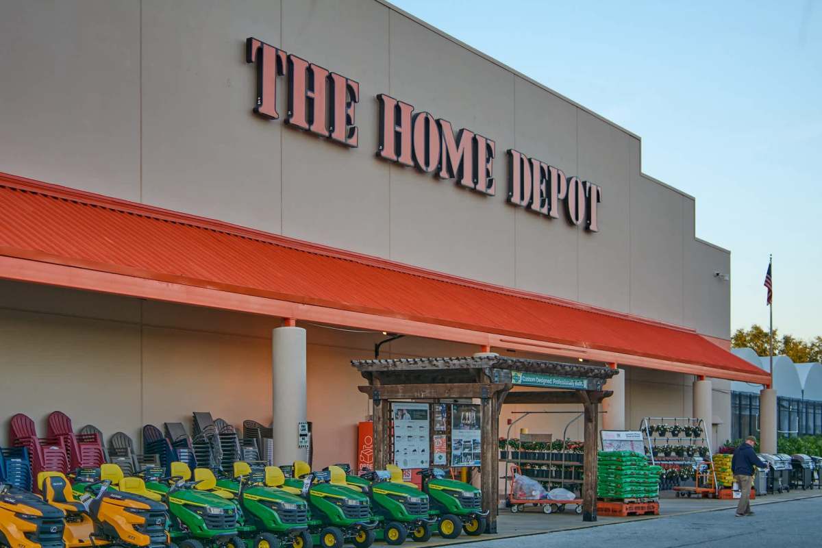 The exterior of a Home Depot store with lawn tractors and gardening supplies displayed outside.