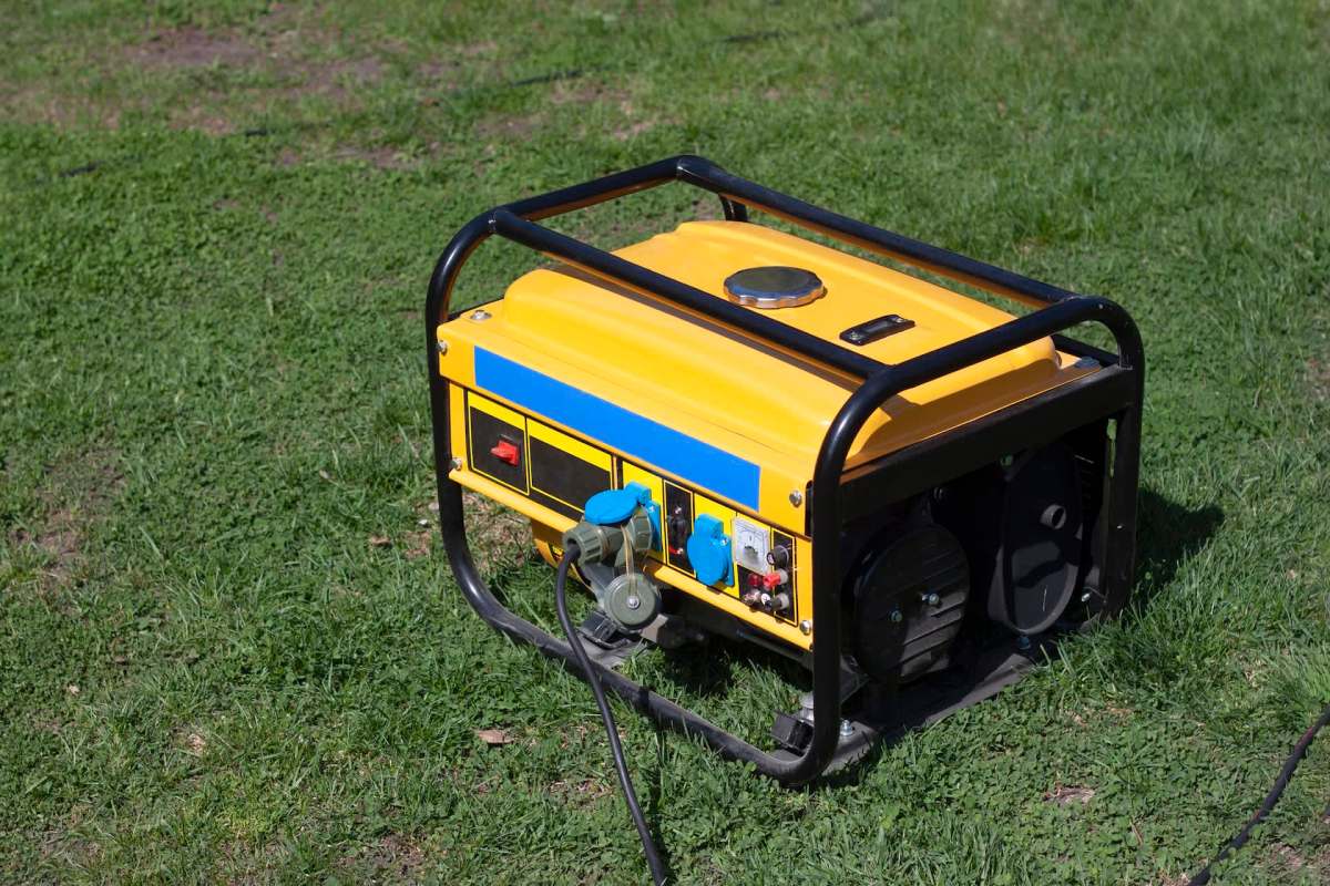 A portable yellow generator on grass.