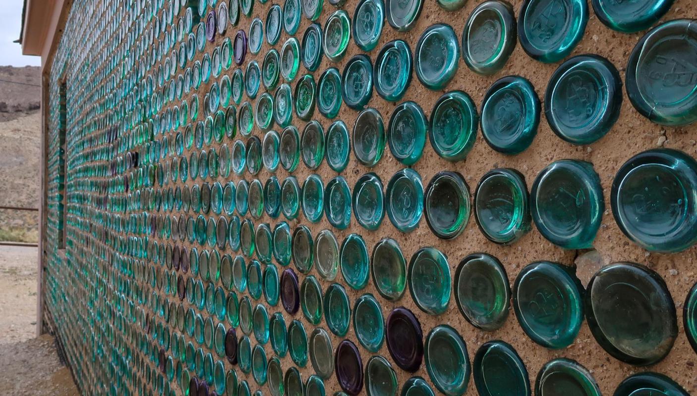 A wall made of glass bottles and adobe.