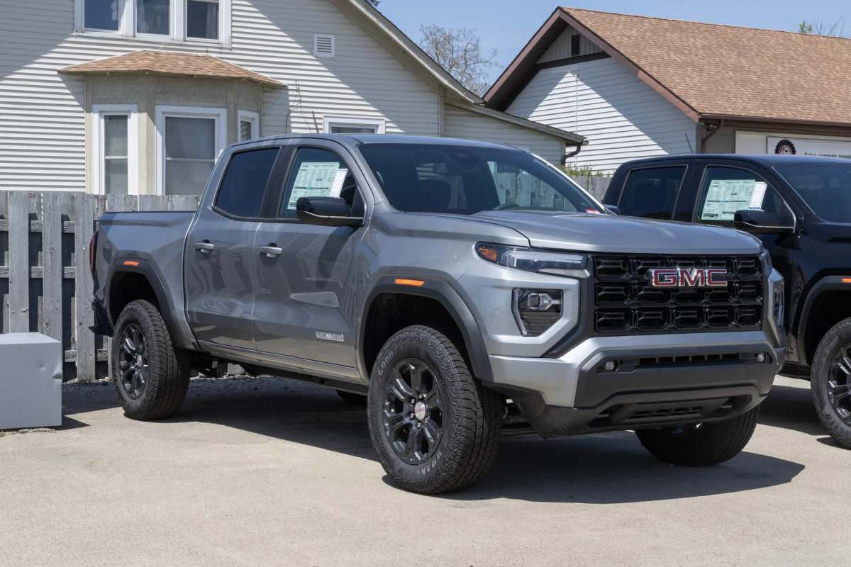 A gray GMC pickup truck parked outside a building with a wooden fence.
