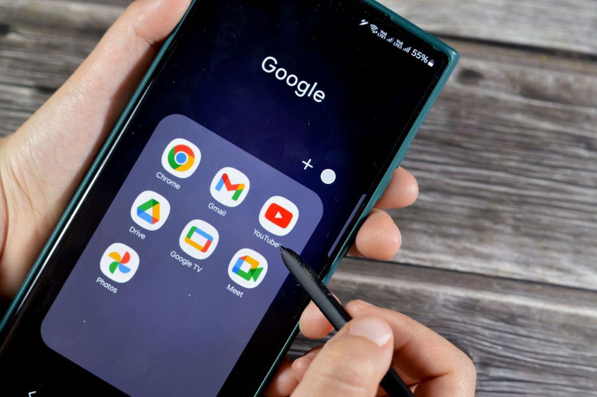 A person holding a phone with Google apps on the screen.