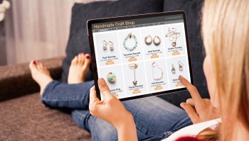 A person browsing a jewelry website on a tablet while sitting on a couch.
