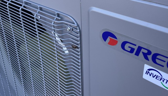 An air conditioning unit with a logo and a small insect on the grill.