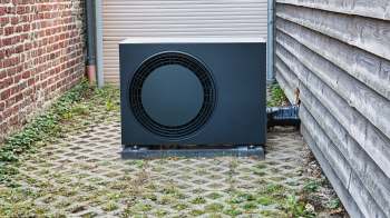 An outdoor heat pump between two walls.