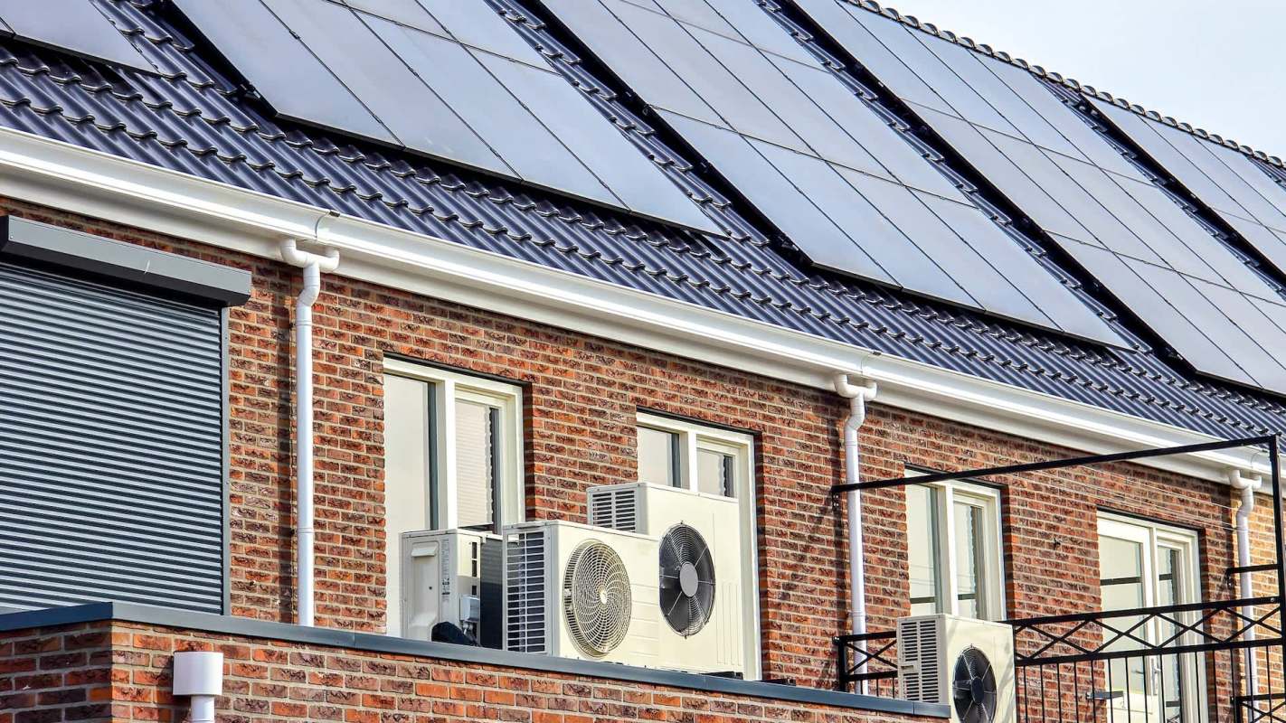 A building exterior with solar panels, windows, and multiple air conditioning units.
