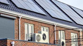 A building exterior with solar panels, windows, and multiple air conditioning units.
