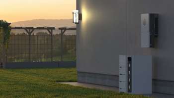 A wall-mounted device and a storage unit are situated beside a grassy area with a trellis and sunset backdrop.