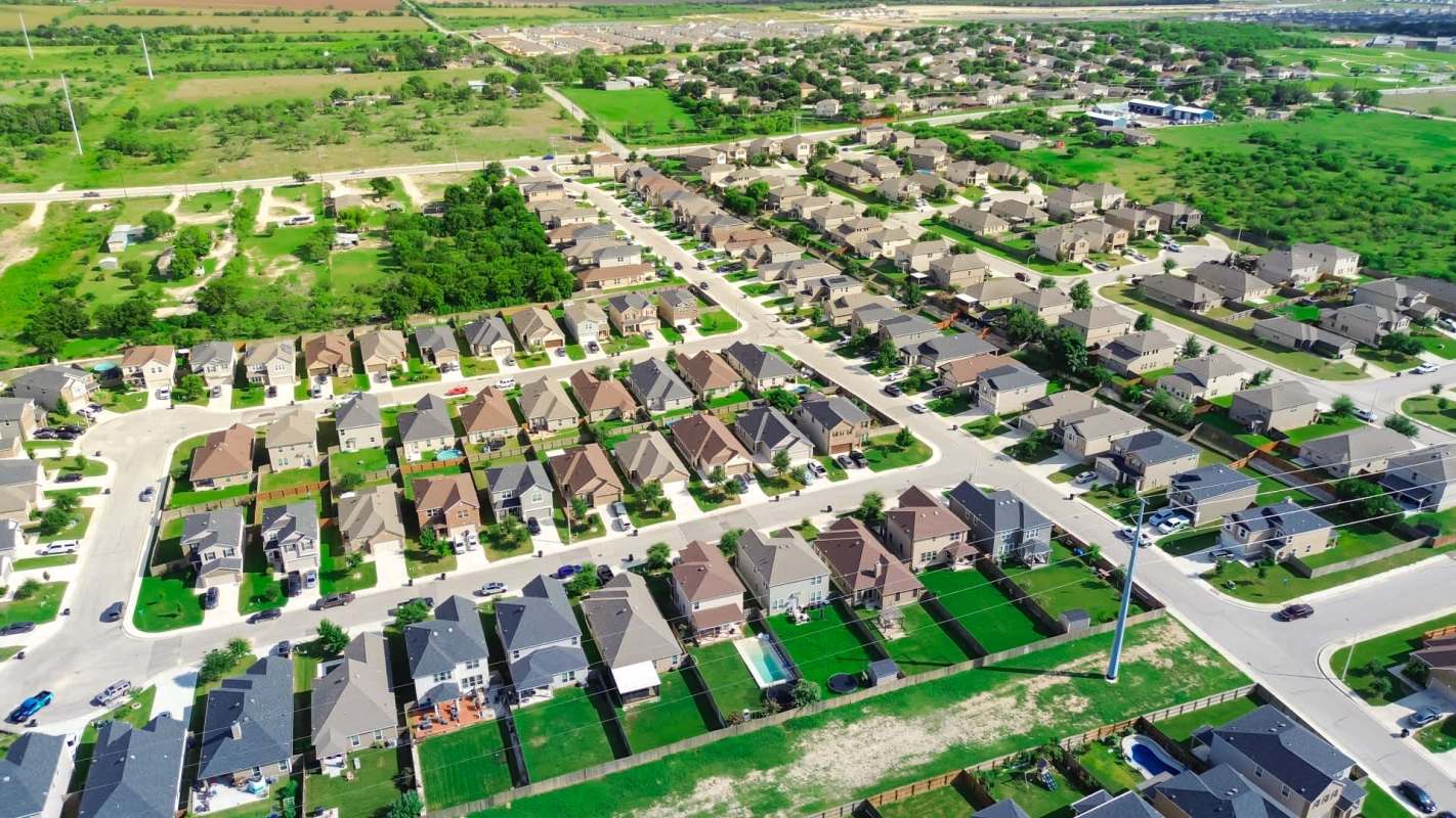 An aerial view of a suburban neighborhood with rows of houses and green lawns.