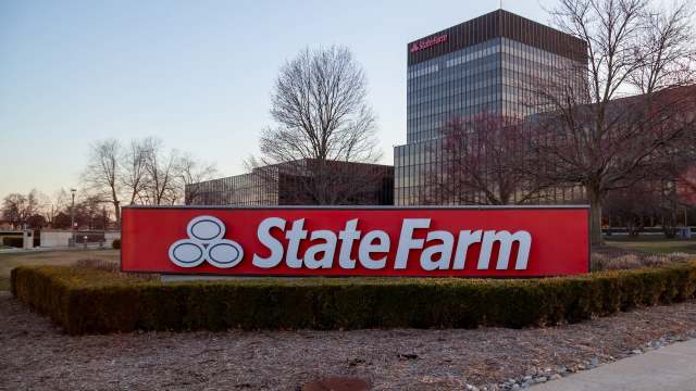 A State Farm sign in front of a corporate building with trees and landscaped shrubs.