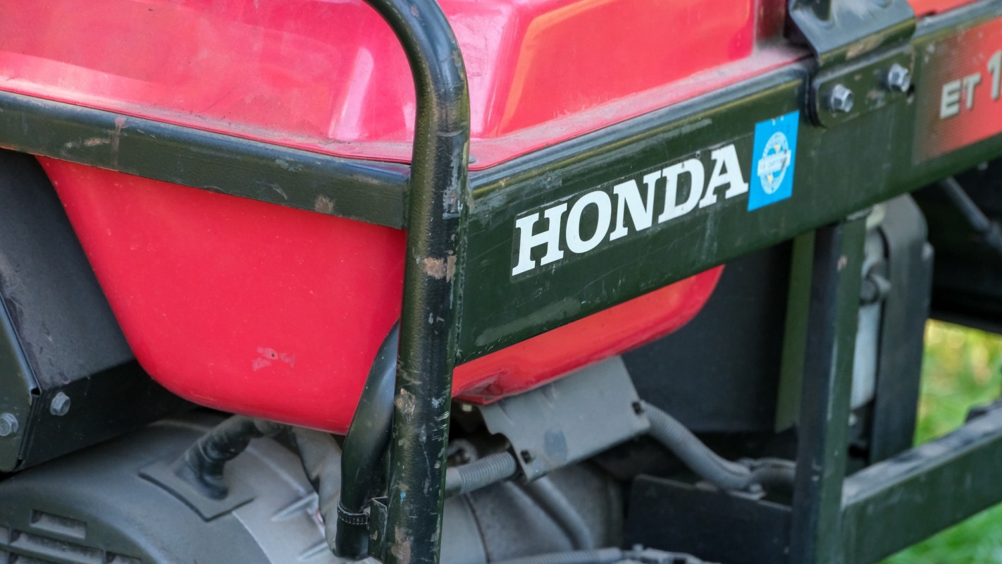 A close-up of a red Honda equipment fuel tank with a black frame.