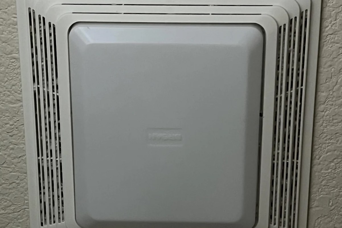 A white wall-mounted ceiling bathroom fan with a rectangular cover and ventilation grilles.