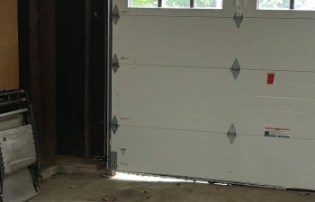 A garage door with a gap at the bottom.