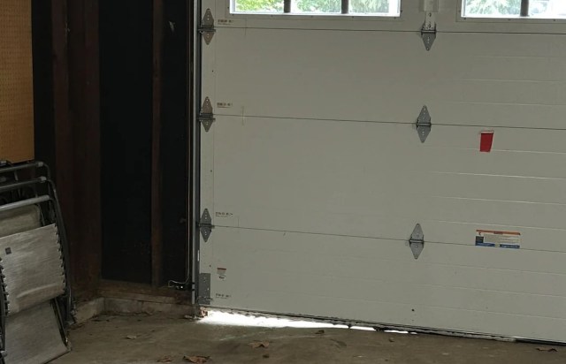 A garage door with a gap at the bottom.