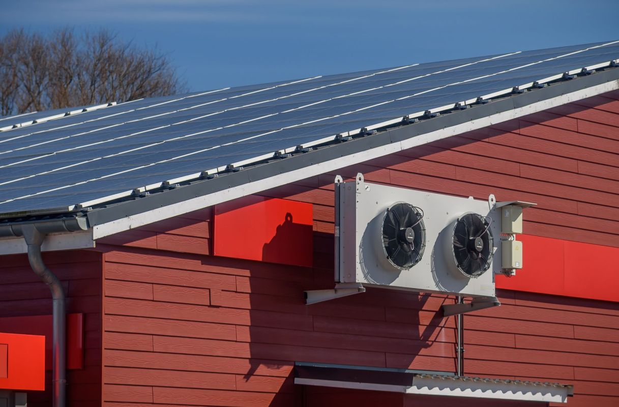 An HVAC unit near roof-mounted solar panels.