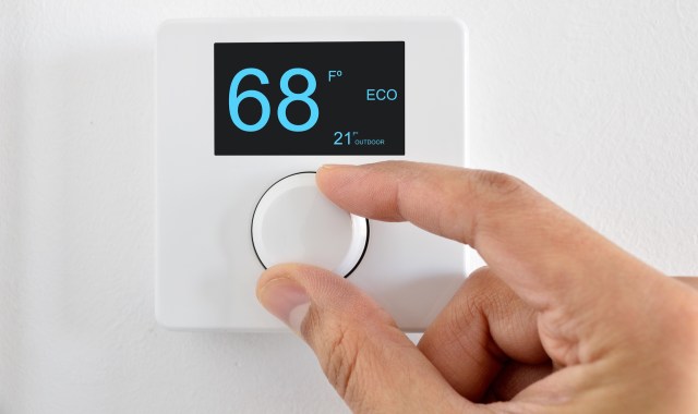 A person adjusting a thermostat.