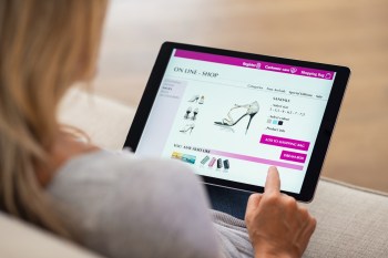 A person browsing an online shopping site for sandals on a tablet.