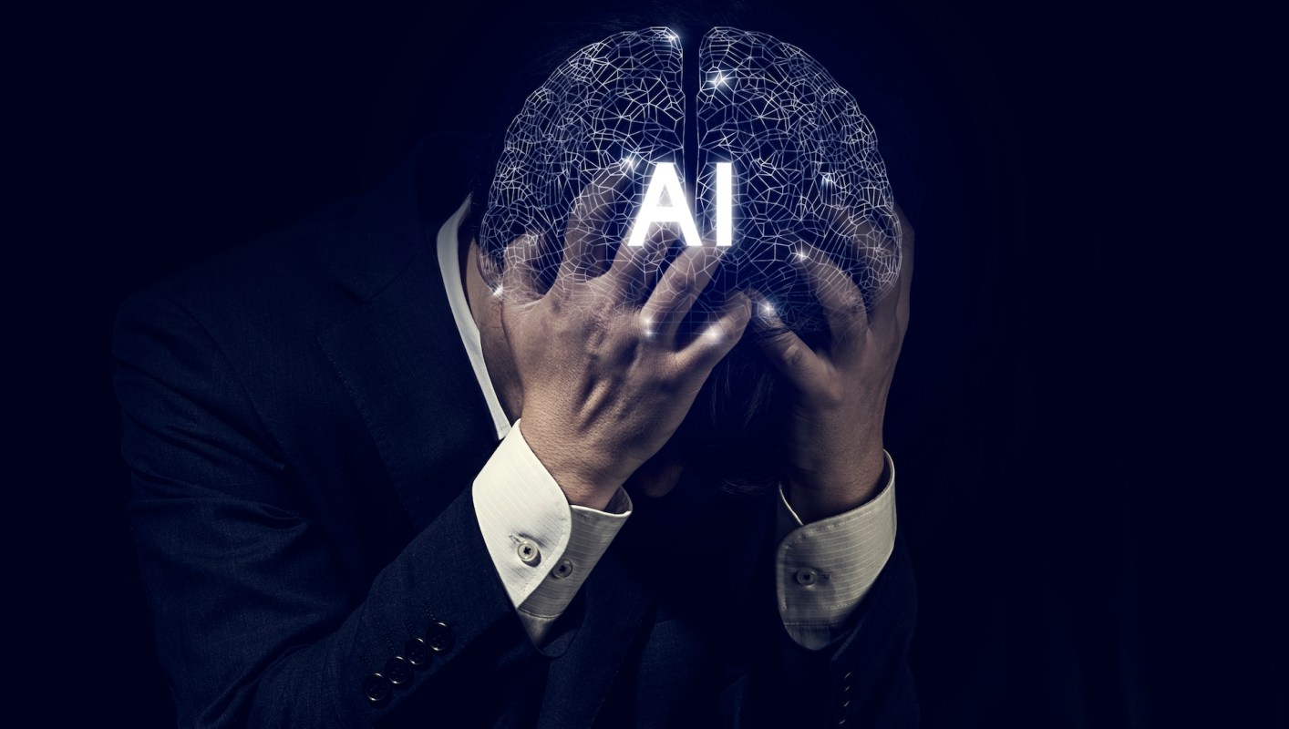 A person in a suit holds their head with a digital brain graphic displaying "AI."