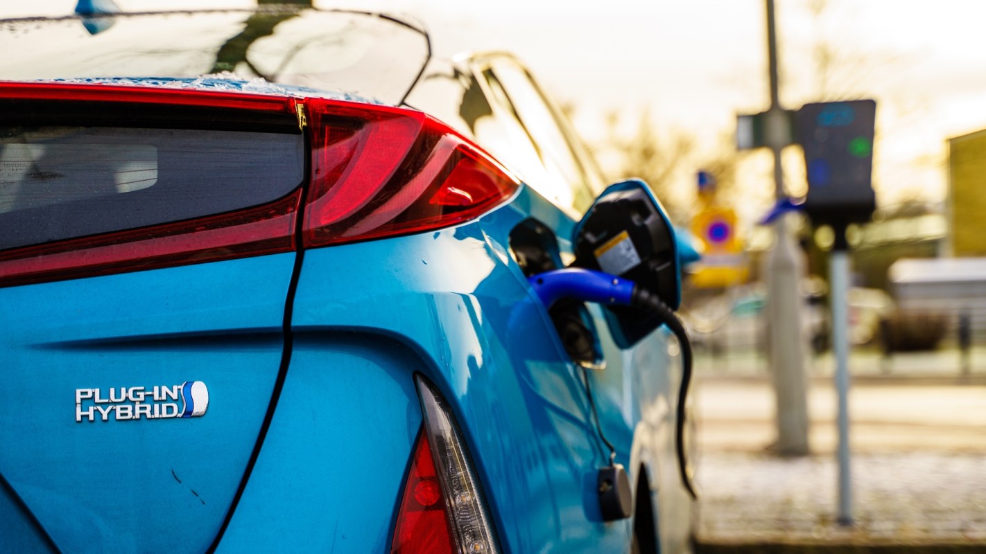 A blue plug-in hybrid car is connected to a charging station.
