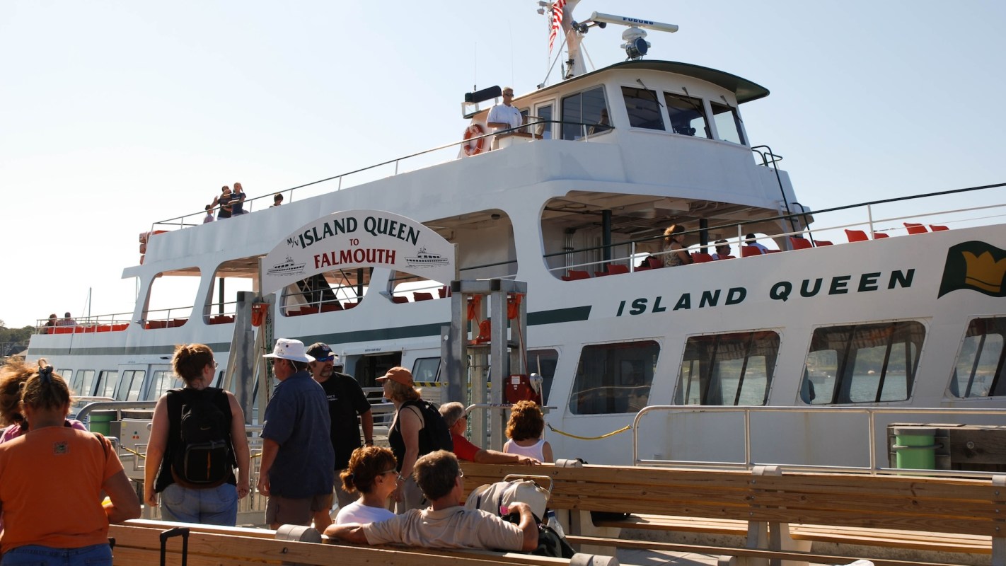 A ferry named "Island Queen" at a dock with people boarding and waiting nearby.