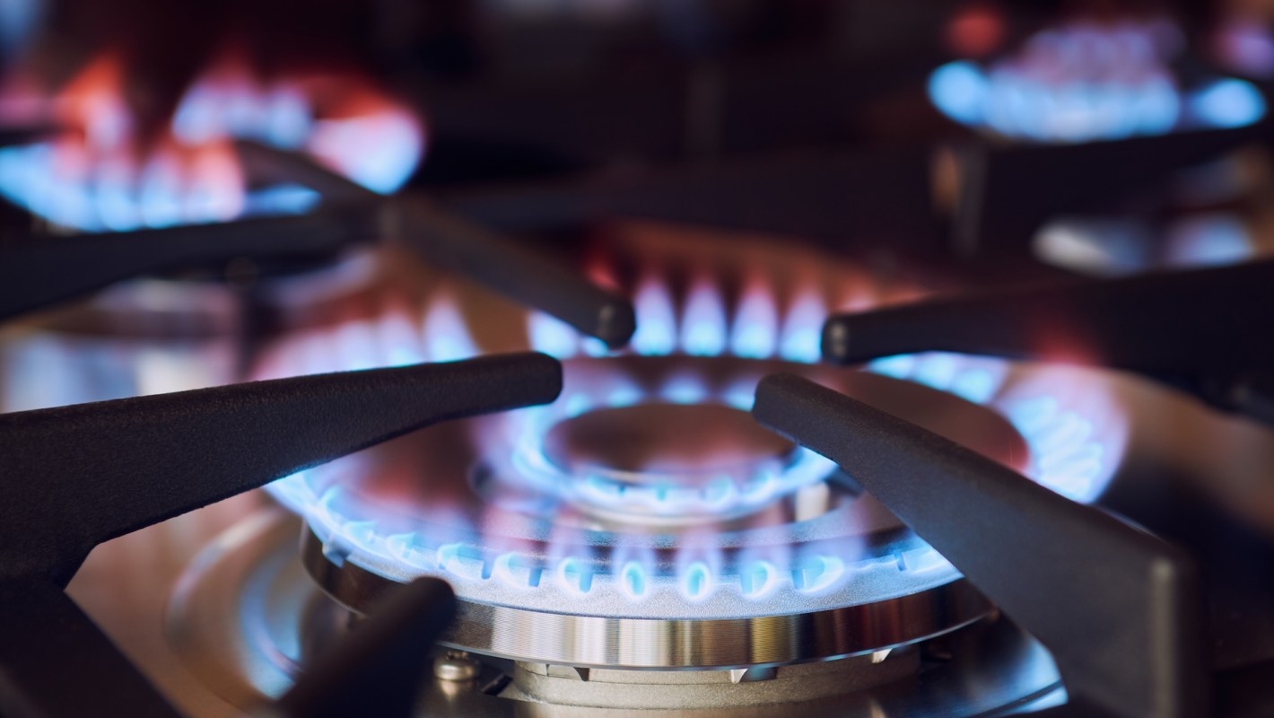 A gas stove with blue flames visible between the burner grates.