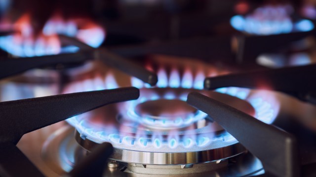 A gas stove with blue flames visible between the burner grates.