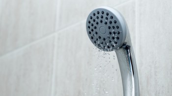 A showerhead with water droplets spraying from it, representing low water pressure.