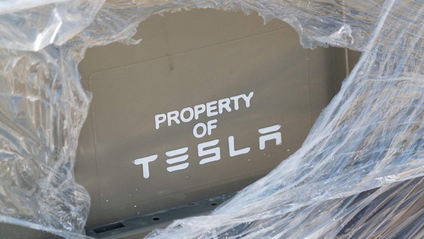 A sign reading "PROPERTY OF TESLA" on a wrapped surface.