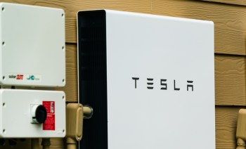 A Tesla Powerwall energy storage unit mounted on a wall alongside electrical equipment.