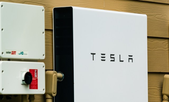 A Tesla Powerwall energy storage unit mounted on a wall alongside electrical equipment.