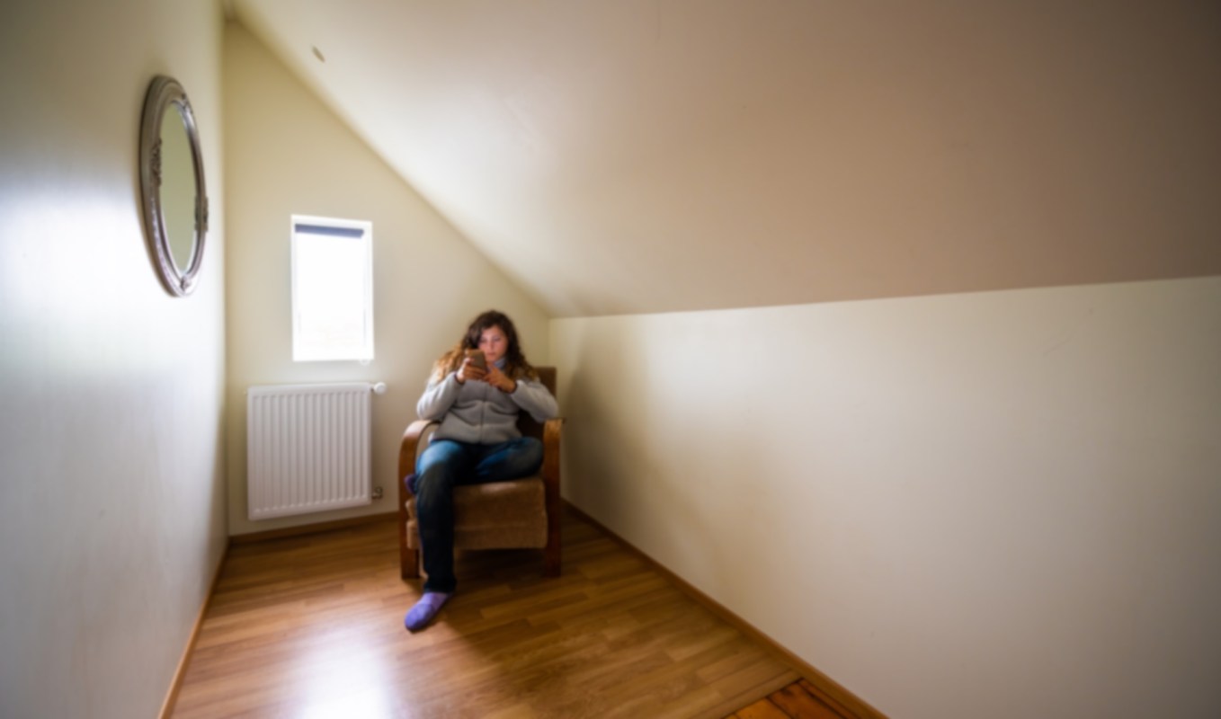 A person sitting in a chair in the corner of a loft.
