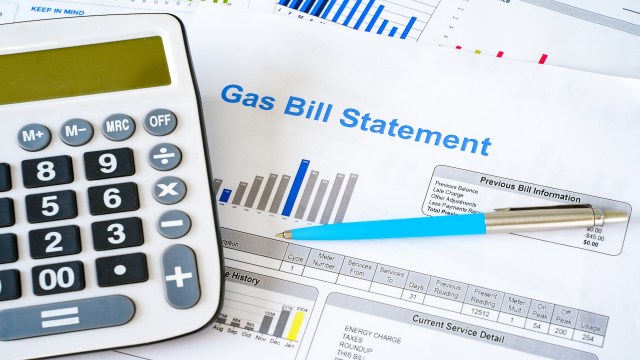 A calculator, a pen, and gas bill statements with charts and payment details.