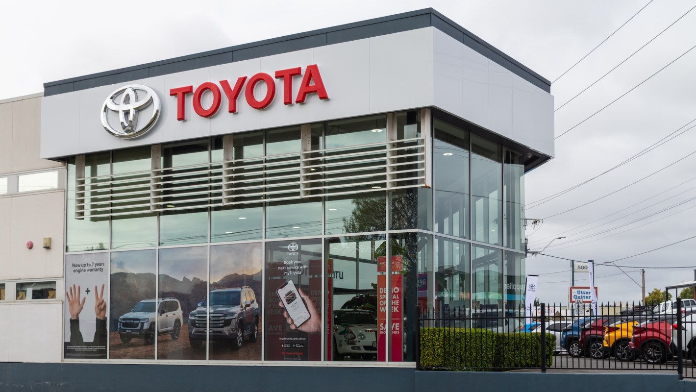 A Toyota dealership with large glass windows displaying cars and promotional signage.