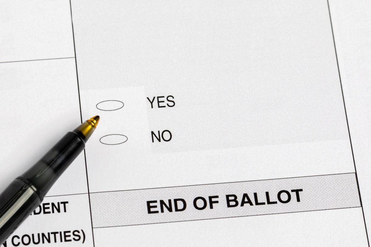A voting ballot with options for "YES" and "NO" and a pen placed beside it.