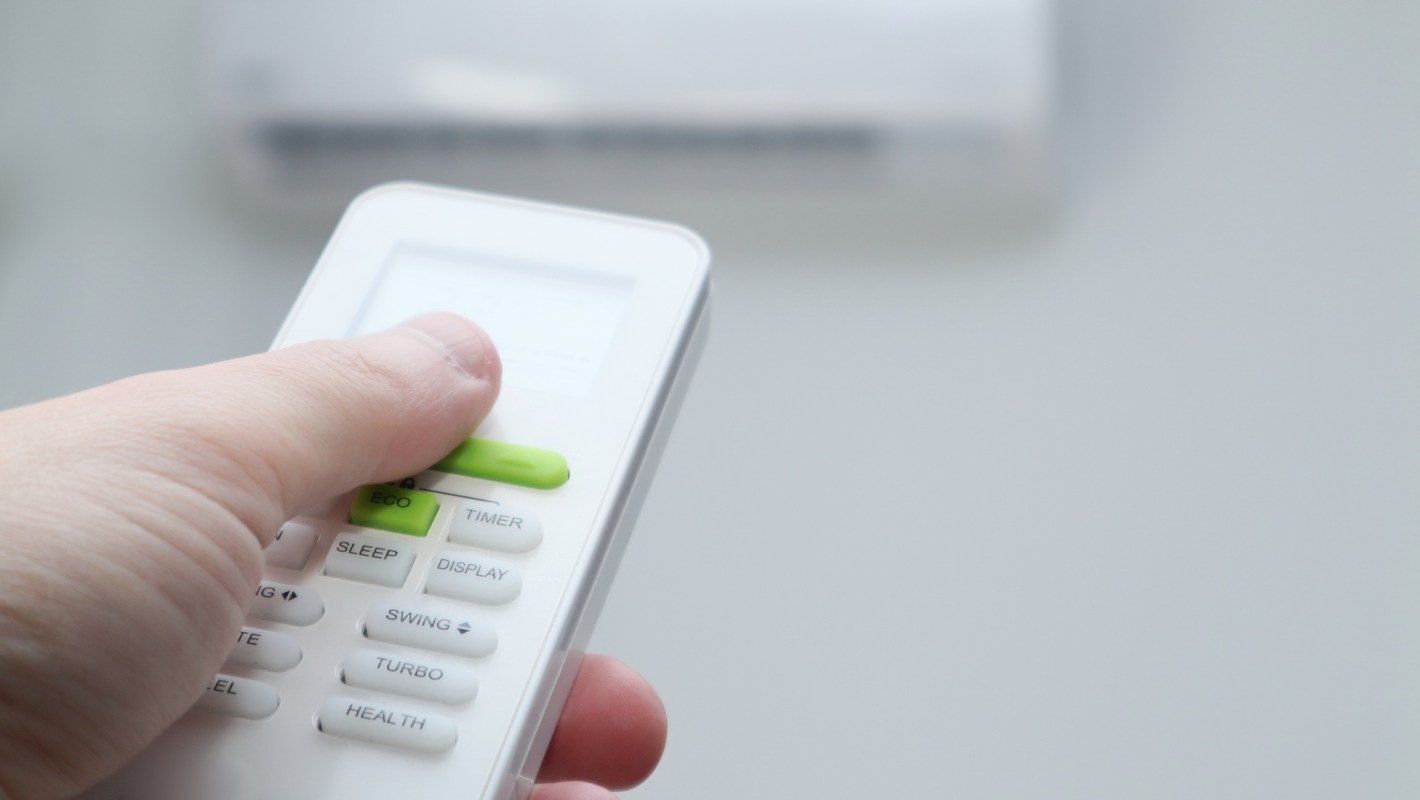 A person uses a remote to adjust a mini-split unit.