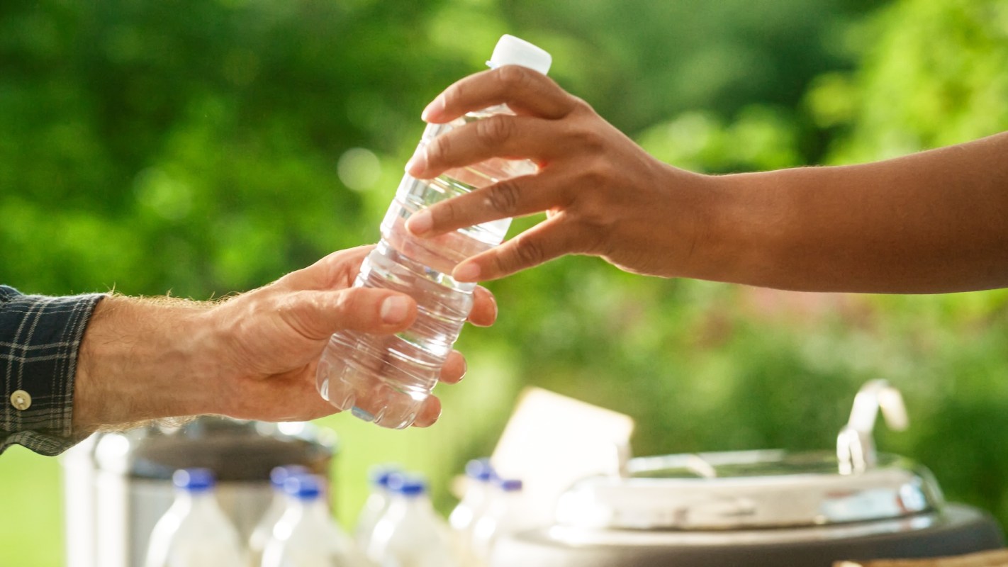 A person handing someone a water bottle.