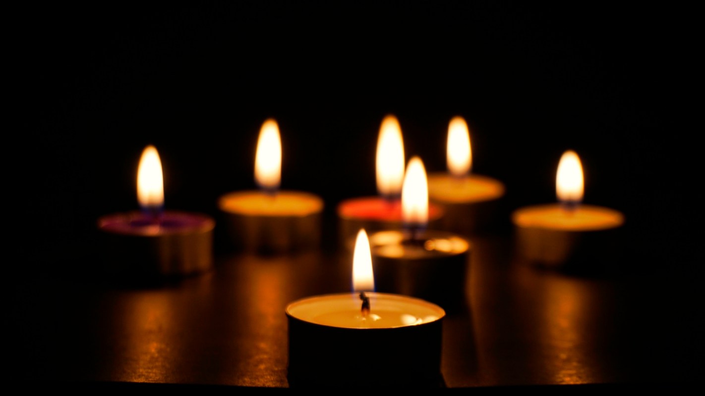 Several lit tealight candles on a dark surface.