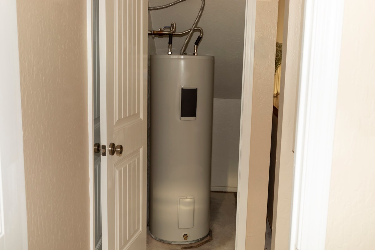 A water heater is located in a narrow space between two doors.