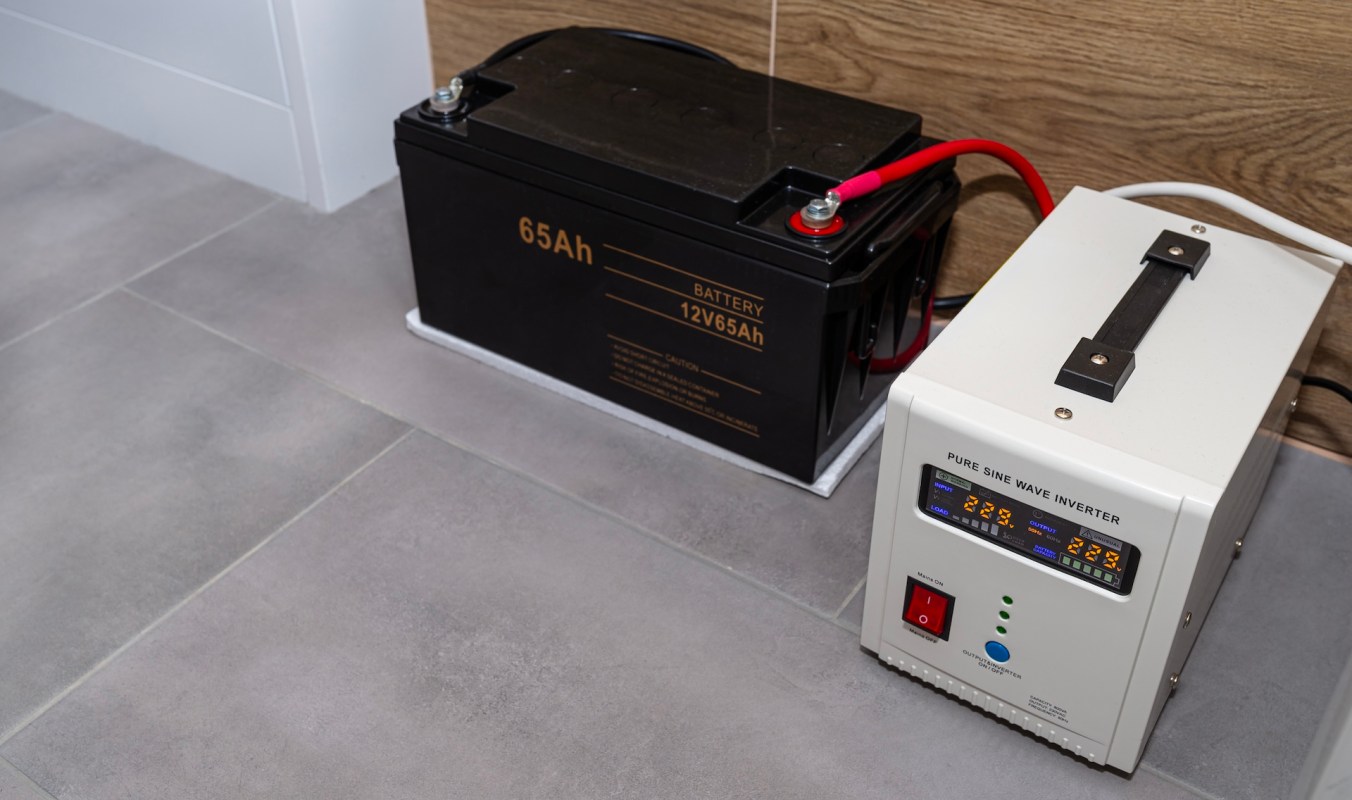 A battery and a pure sine wave inverter positioned on a gray tiled floor.