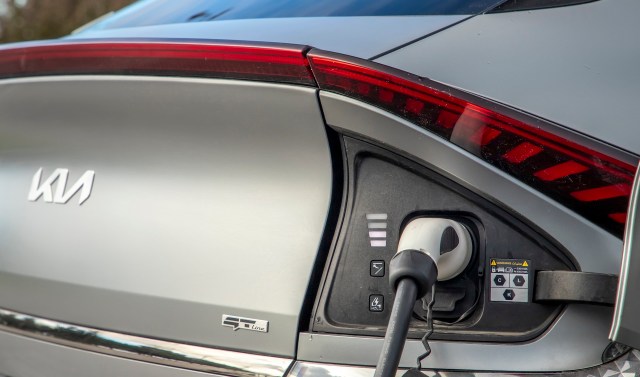 A Kia electric vehicle charging port with a connector plugged in.